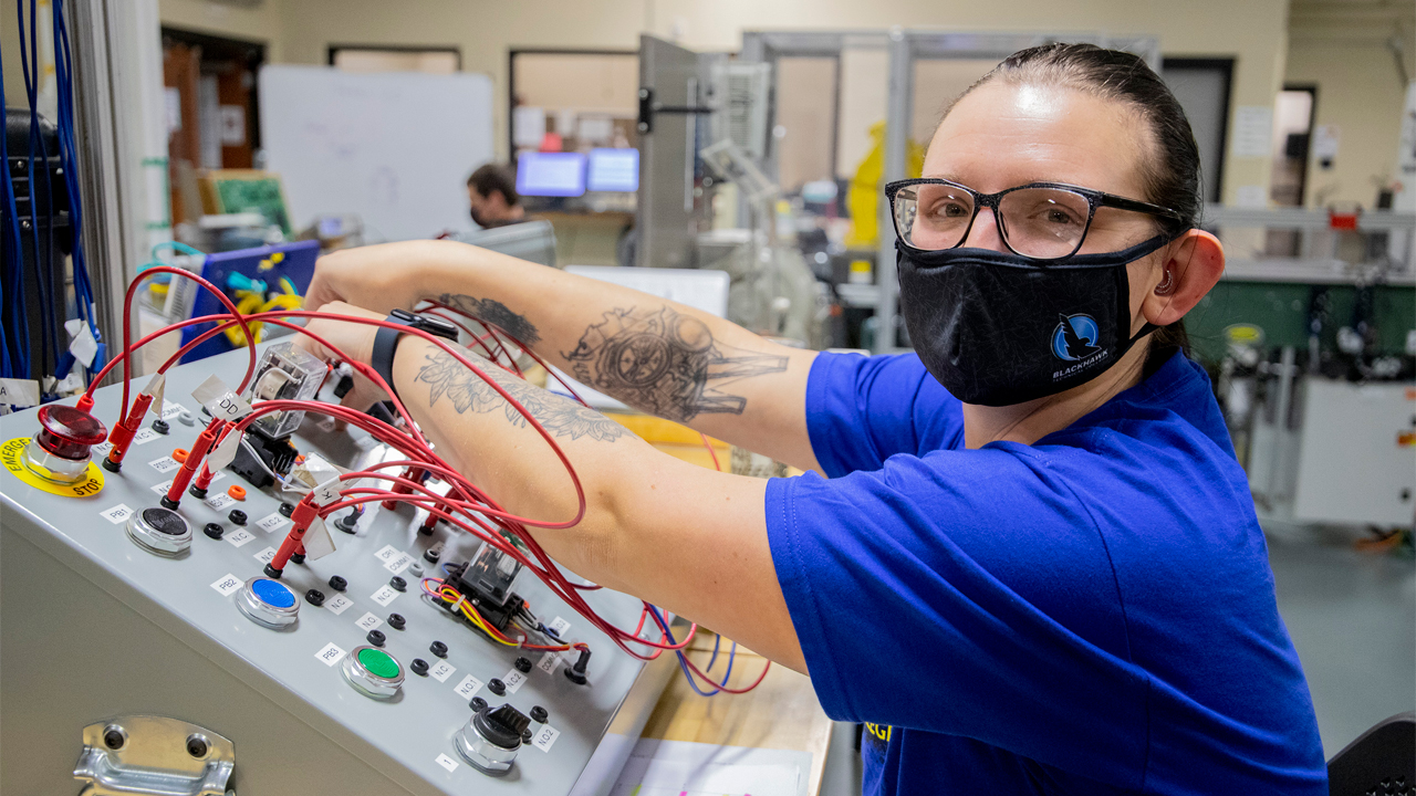 A student using a relay trainer. It is used to practice wiring different motor control circuits.